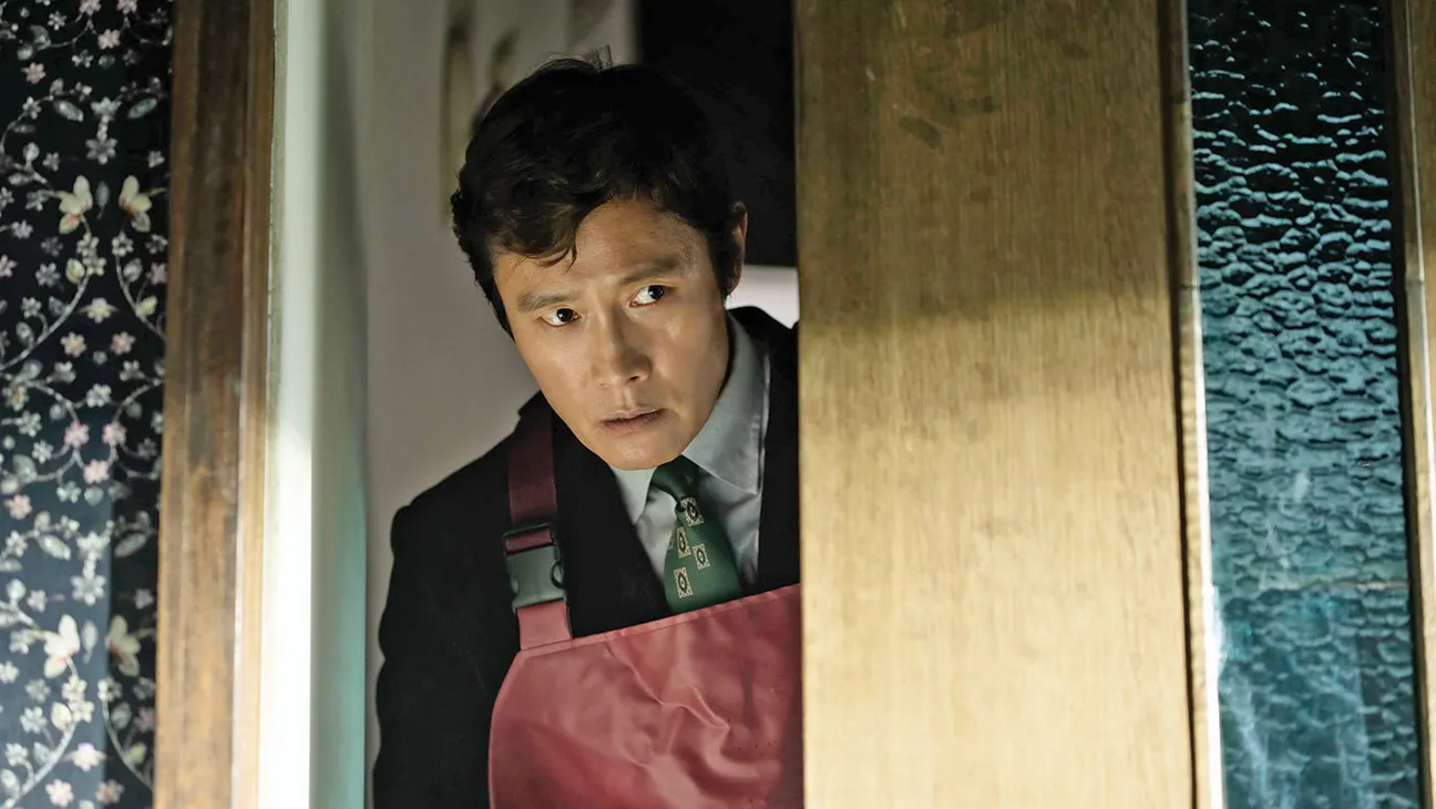 Lee Byung-hun stands in a doorway in Park Chan-wook’s workplace satire, “No Other Choice"